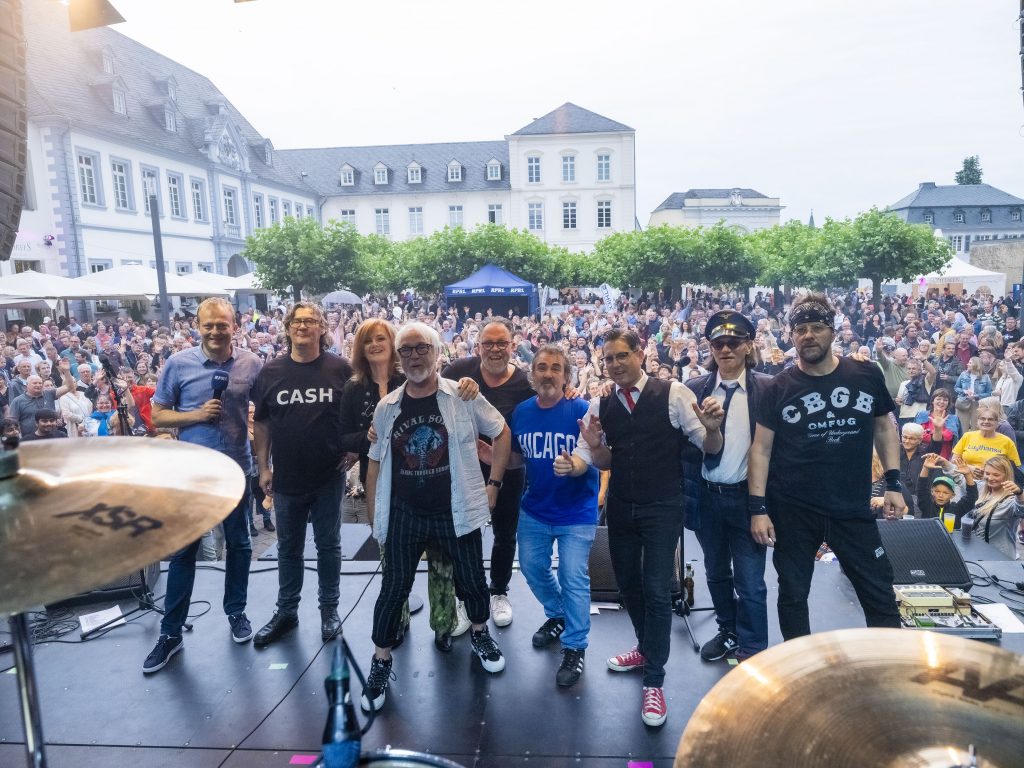 Gruppenfoto von der Band Lusthansa während eines Live-Konzerts auf der Bühne mit vielen Zuschauern