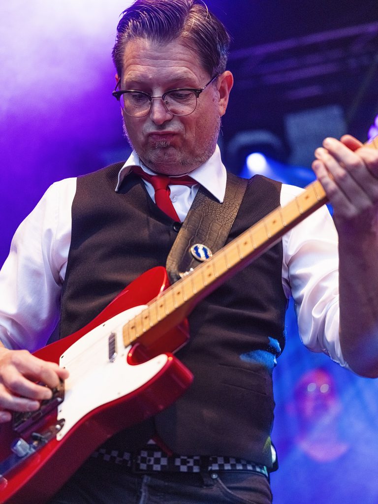 Lusthansa Mitglied spielt Bass in der Farbe rot auf einem Konzert