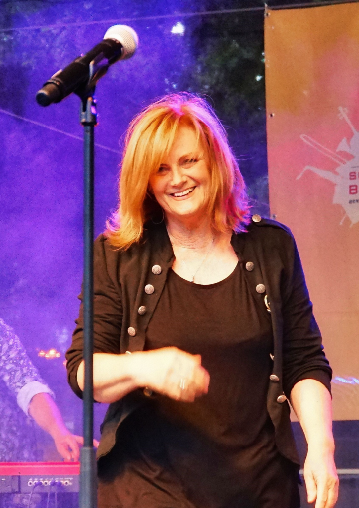 Lusthansa Bandmitglied Jutta Pardeike lächelt in die Kamera während eines Auftritts